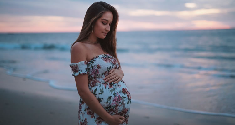 Picture of a pregnant woman walking along the beach.