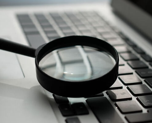 A picture of a magnifying glass and a laptop computer representing Keyword Research.